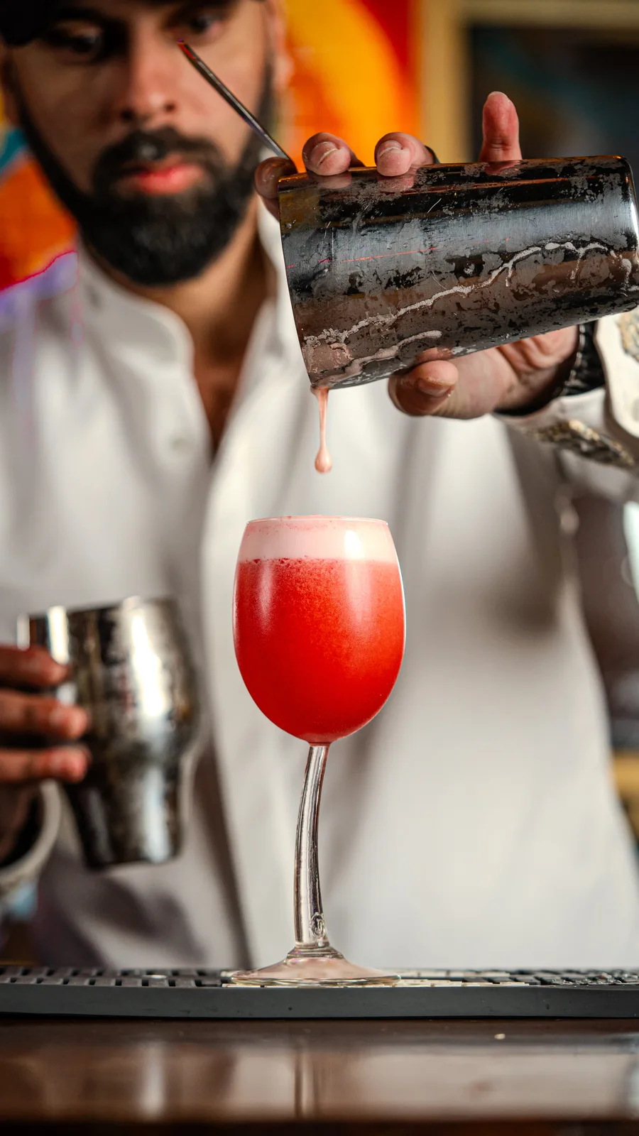 Bartender versant un cocktail rouge