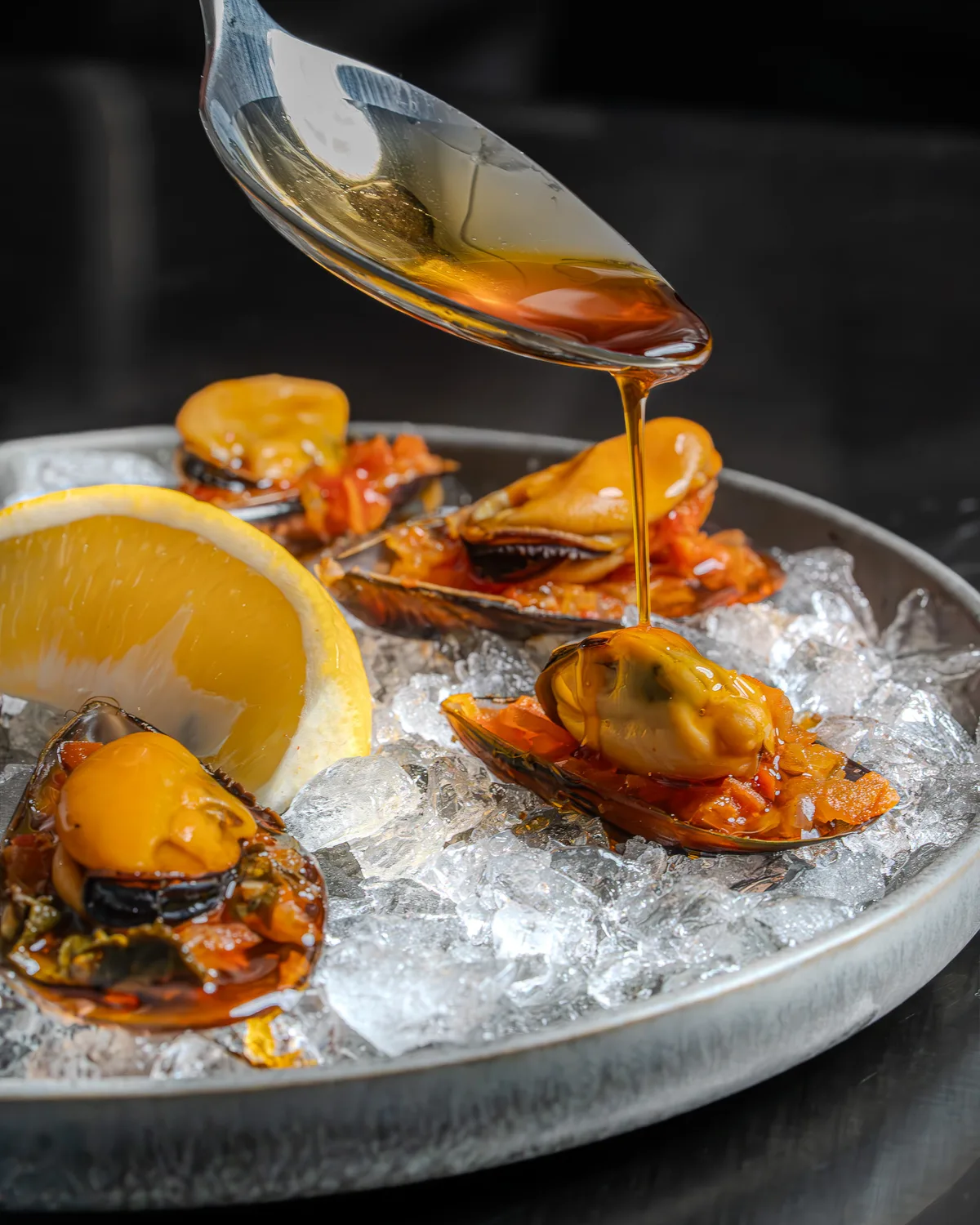 Sauce ambrée versée sur une assiette de moules Le Ninety