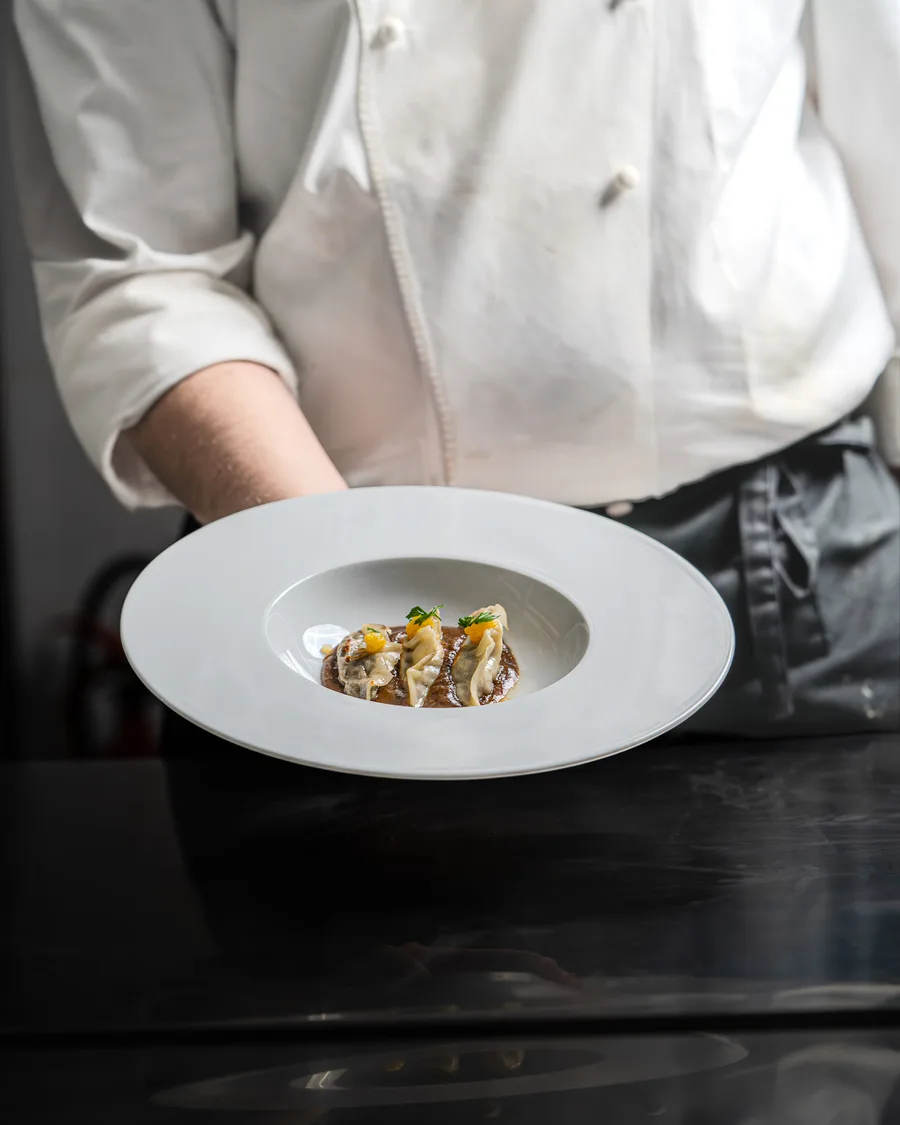Chef présentant une assiette blanche dressée