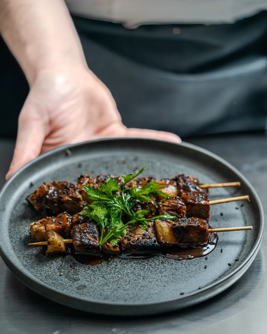 Brochettes grillées présentées sur une assiette sombre