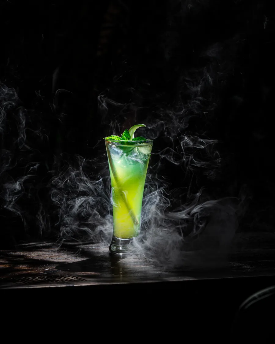 Cocktail vert fumant sur une table sombre